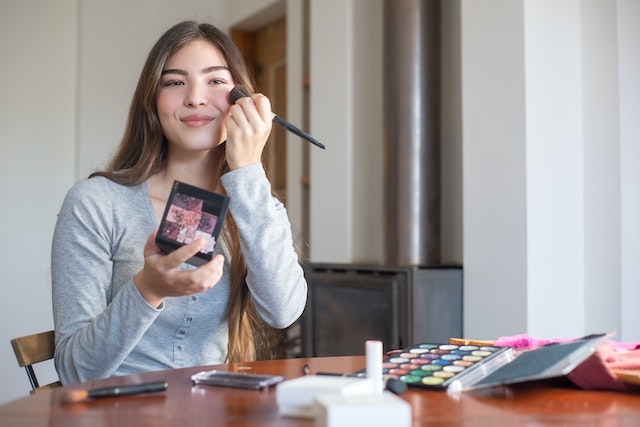 A person doing their make up on a desk