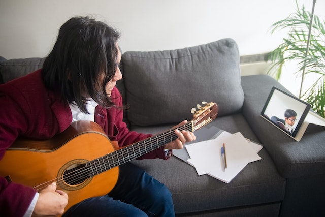 A person teaching guitar on a laptop