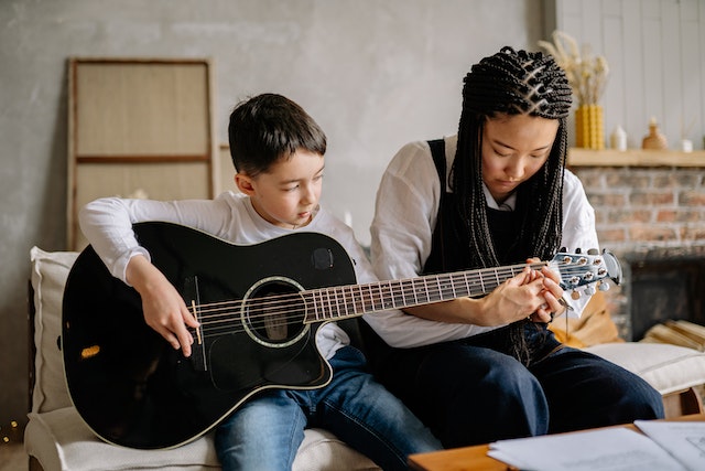 A woman teaching guitar to a child