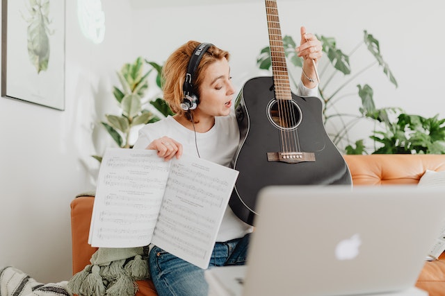 A woman teaching guitar online on a macbook