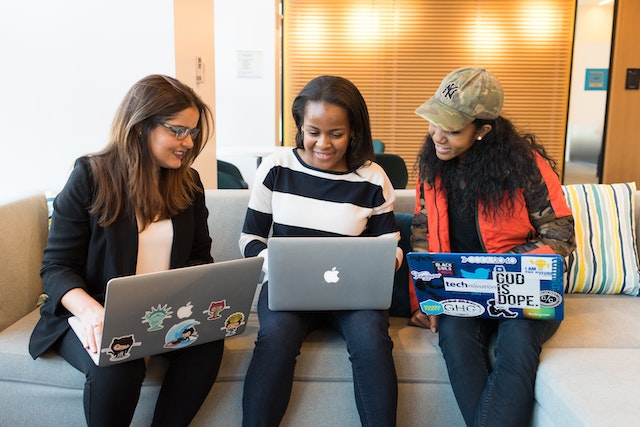 Three people with laptops discussing something together