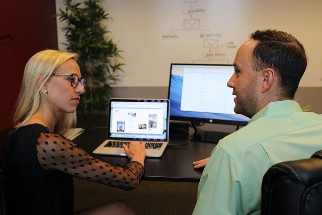 Two people in front of computers discussing