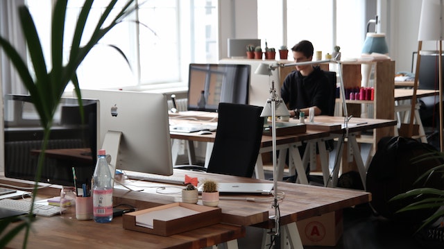 A small workspace with people and desktops and laptops