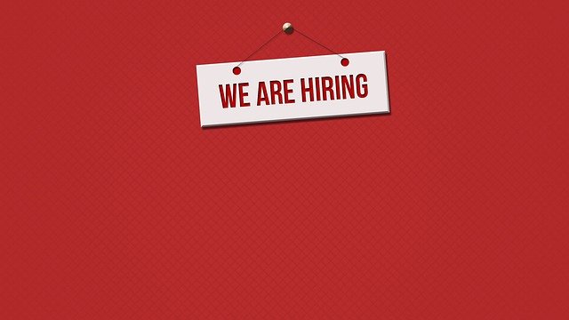 We're Hiring poster on a red wall