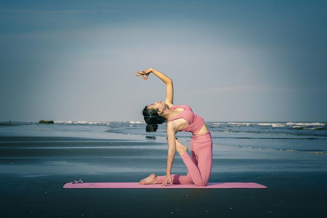 A woman doing yoga outdoors on a beach