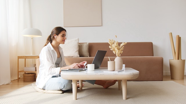 Woman learning in their living room in front of a sofa