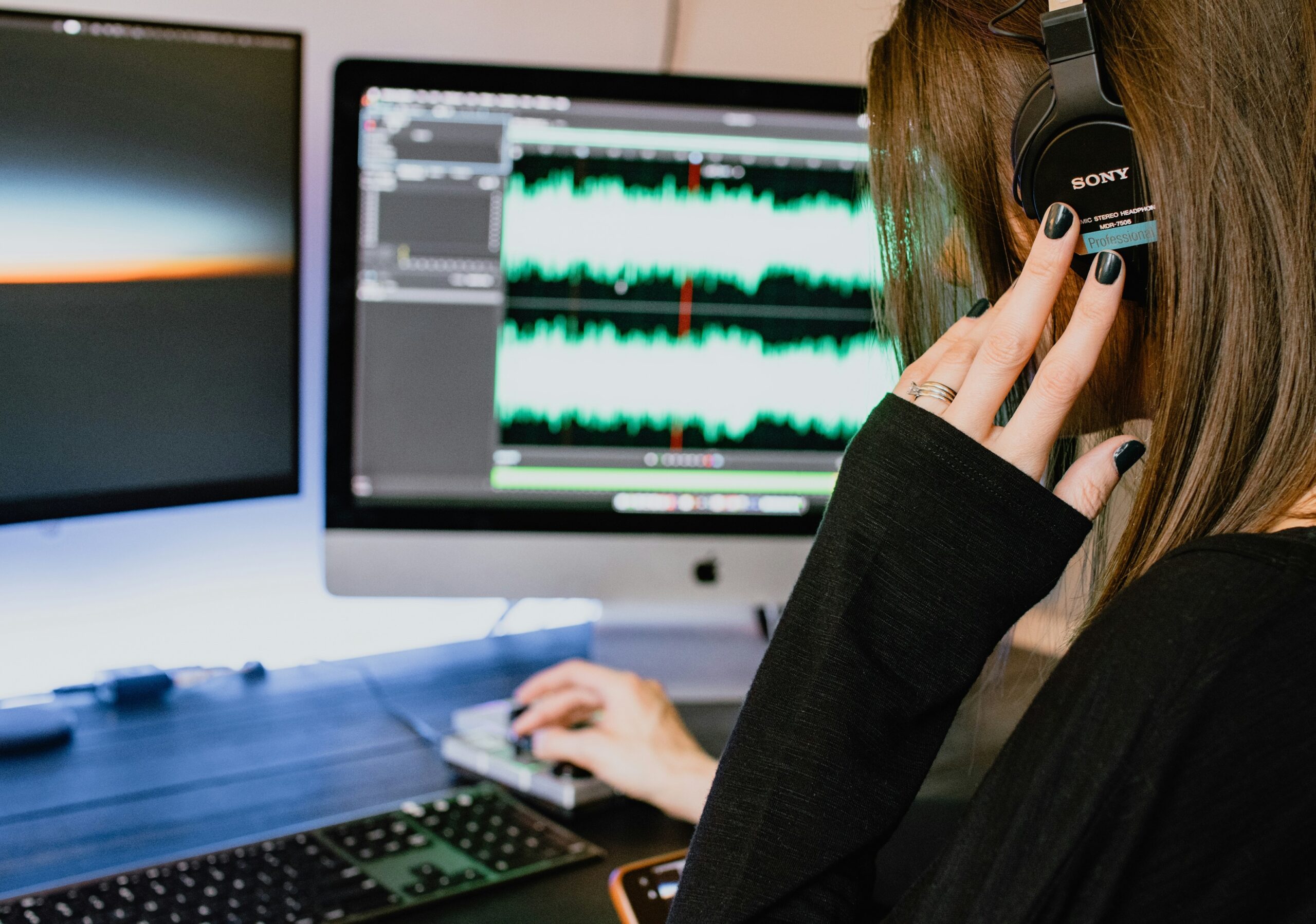 a woman wearing headphones in front of an LMS for music schools on a computer